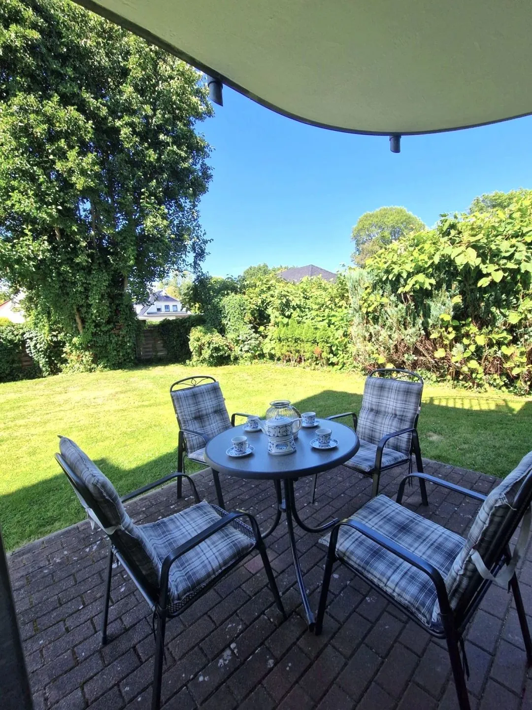 Überdachte Terrasse mit gedecktem Tisch und Blick in den grünen Garten